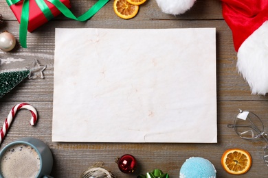 Photo of Flat lay composition with empty card and Christmas decorations on wooden table, space for text. Writing letter to Santa Claus