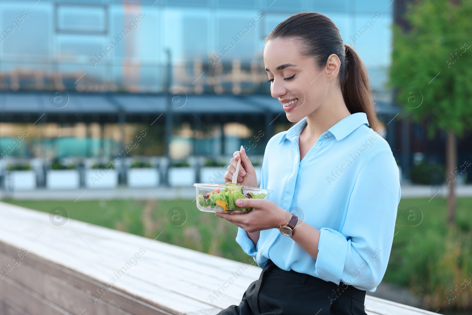 Photo of Smiling businesswoman eating lunch outdoors. Space for text