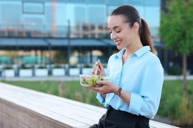 Photo of Smiling businesswoman eating lunch outdoors. Space for text