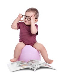 Little child with glasses and book sitting on baby potty against white background