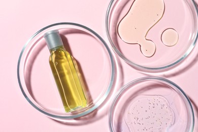 Many Petri dishes and cosmetic products on pink background, flat lay