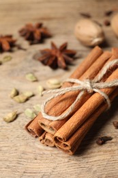 Cinnamon sticks and other spices on wooden table, closeup