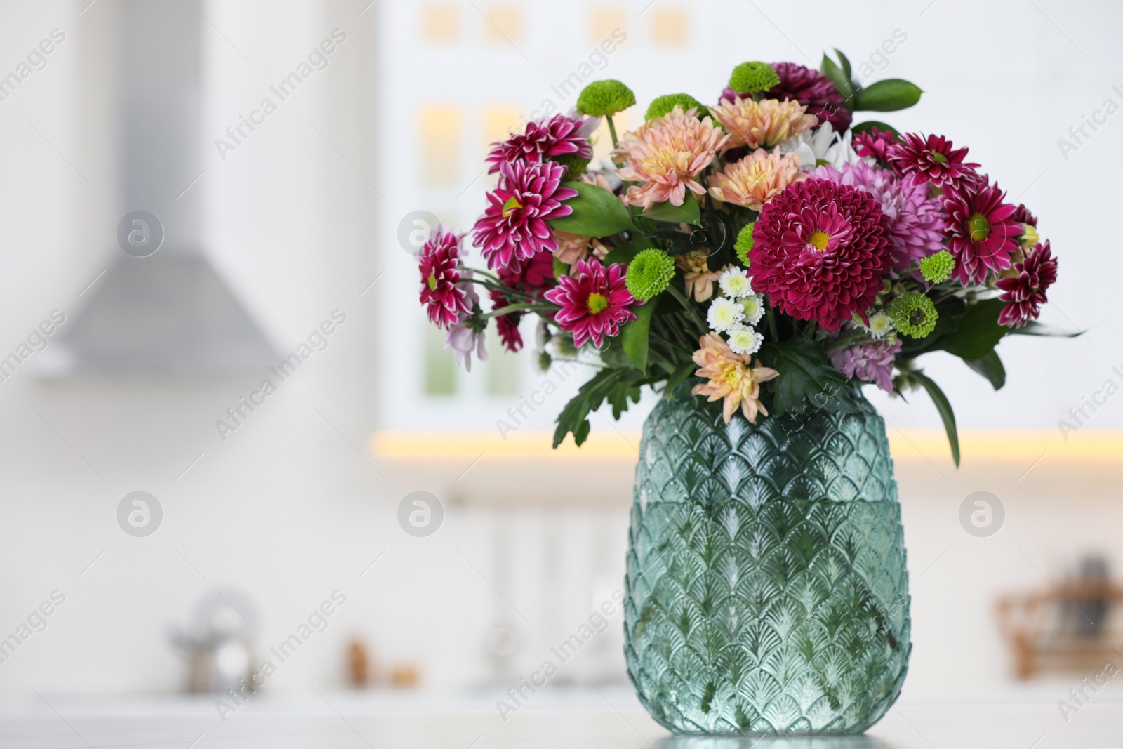 Photo of Bouquet of beautiful chrysanthemum flowers on table in kitchen, space for text