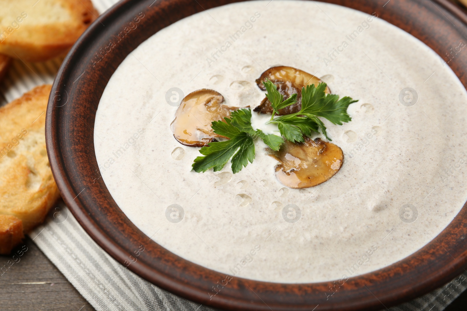 Photo of Fresh homemade mushroom soup in ceramic bowl on wooden table, closeup