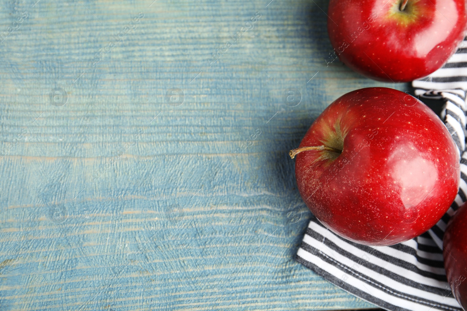 Photo of Ripe juicy red apples on blue wooden background, flat lay. Space for text