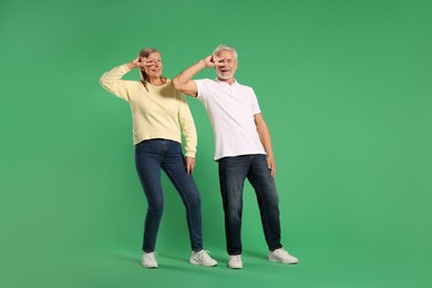 Senior couple dancing together on green background