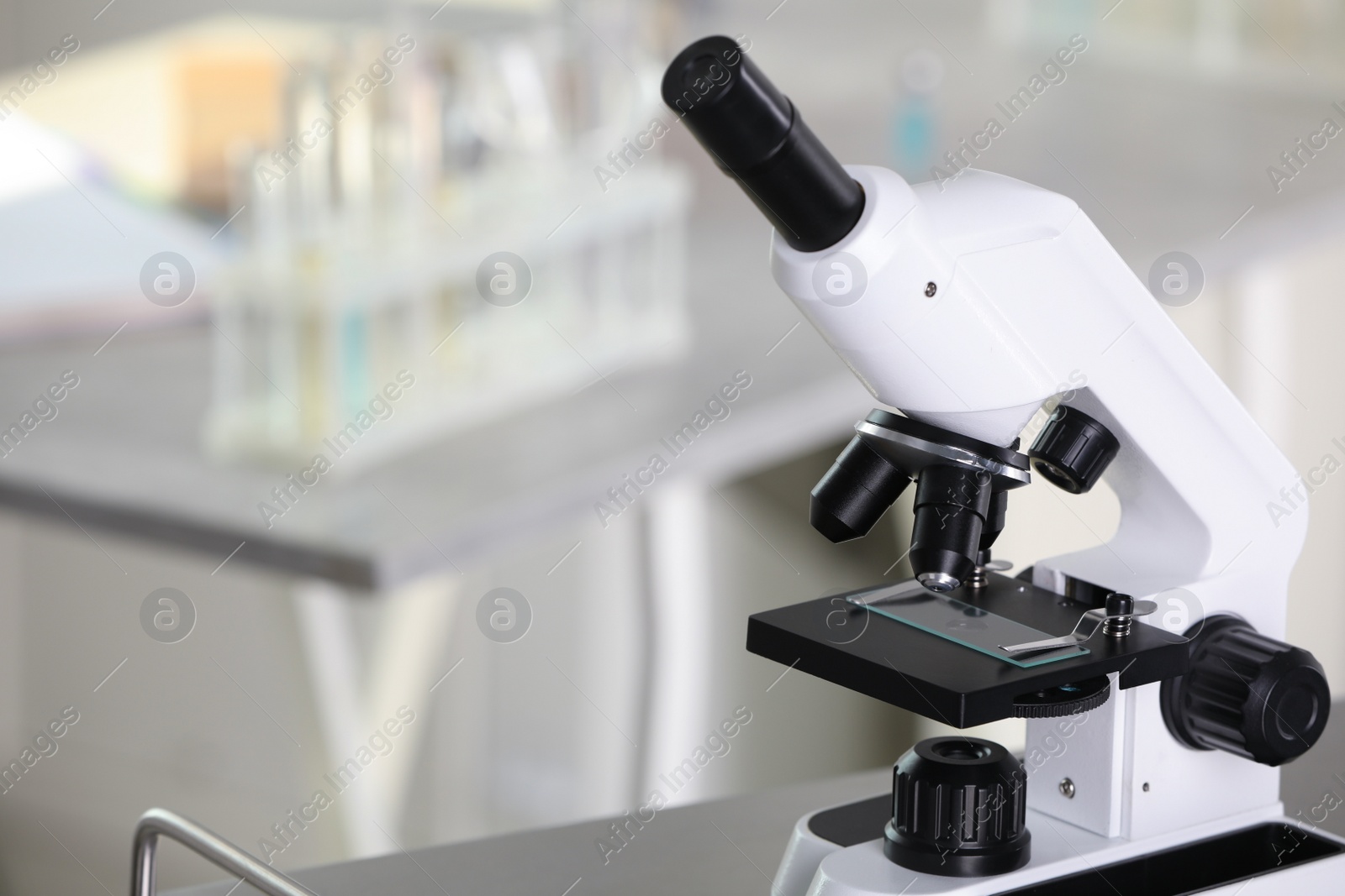 Photo of Modern medical microscope on metal table in laboratory, space for text