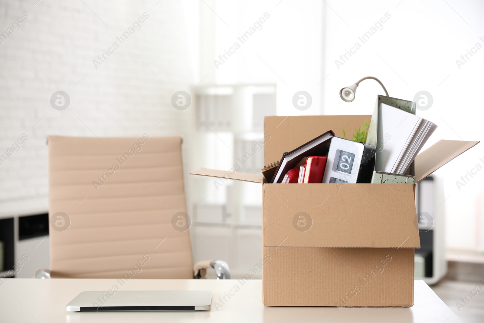 Photo of Cardboard box full of stuff on table in office