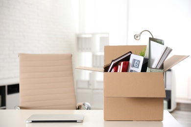 Photo of Cardboard box full of stuff on table in office