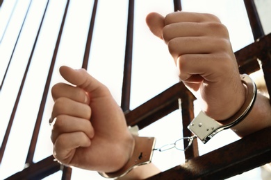 Man handcuffed in jail outdoors, closeup. Criminal law
