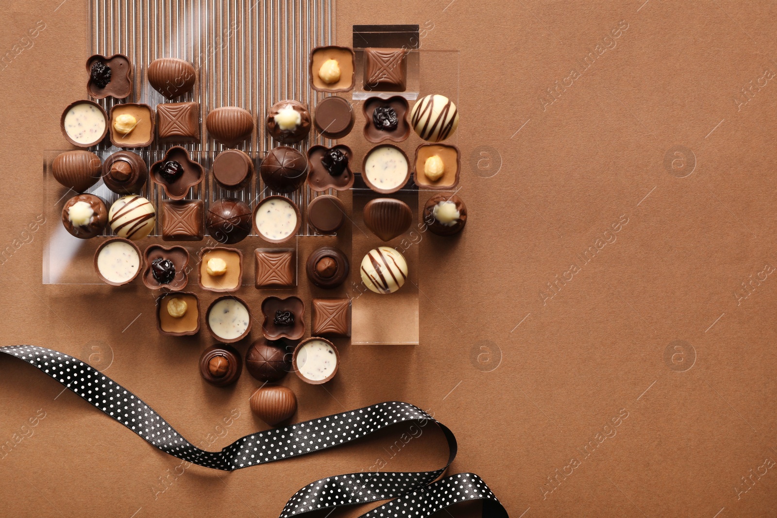 Photo of Heart made with delicious chocolate candies on brown background, top view. Space for text