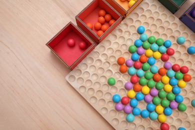 Photo of Wooden sorting board and boxes with colorful balls on table, top view. Montessori toy