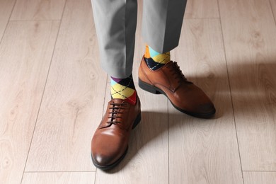 Photo of Man wearing stylish shoes and colorful socks indoors, closeup