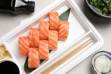 Delicious sushi rolls served on light grey marble table, flat lay. Food delivery