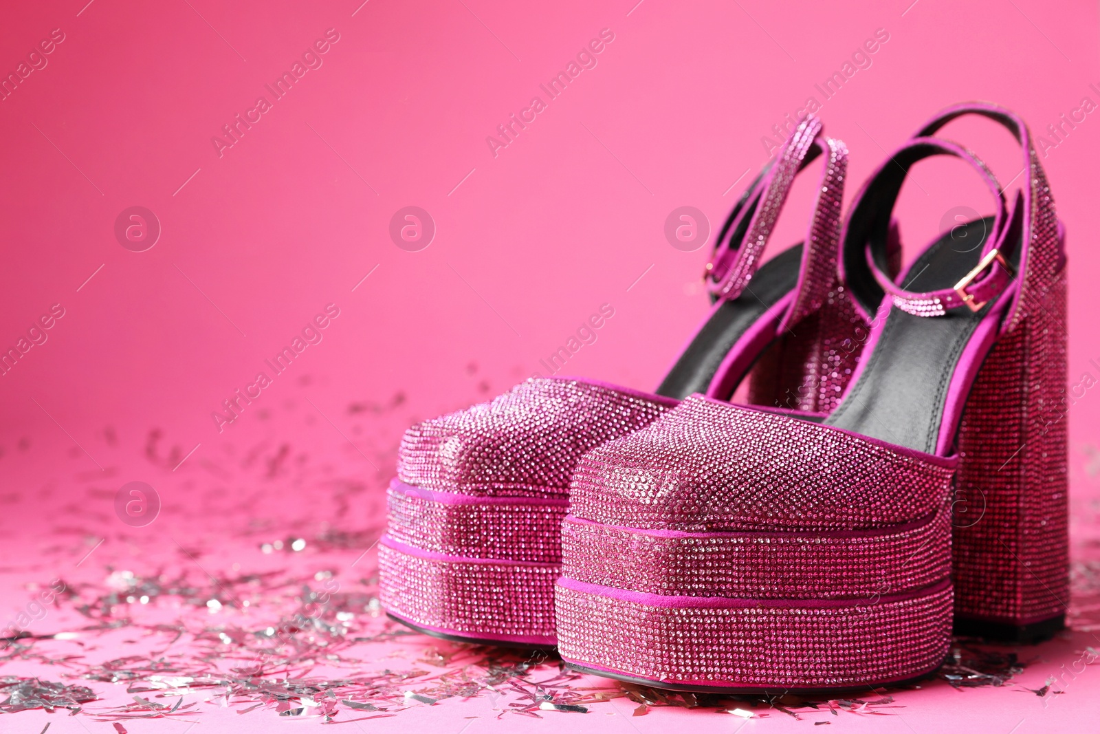 Photo of Fashionable punk square toe ankle strap pumps and confetti on pink background, space for text. Shiny party platform high heeled shoes