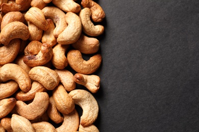 Tasty cashew nuts on black background, top view. Space for text