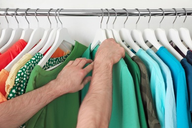 Man choosing clothes from rack in wardrobe, closeup