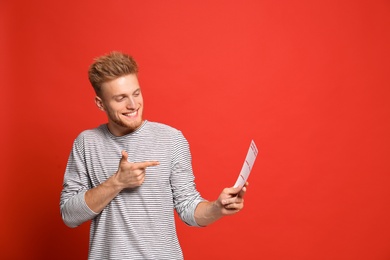 Photo of Portrait of happy young man with lottery ticket on red background