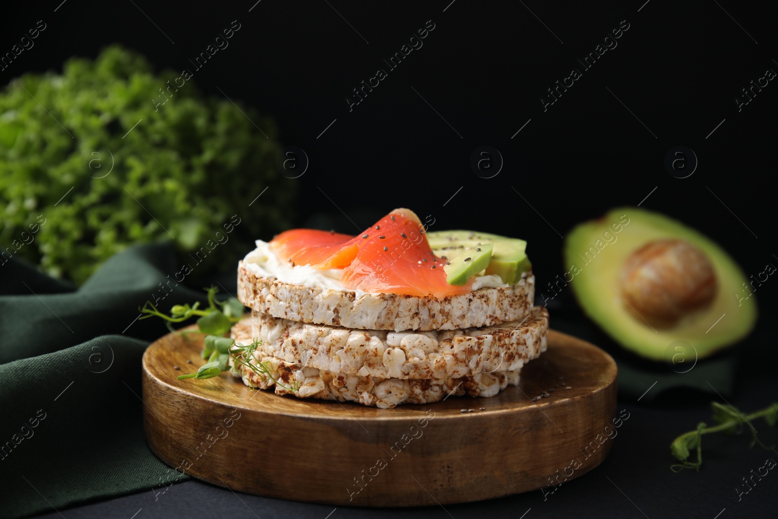 Photo of Crunchy buckwheat cakes with cream cheese, salmon and avocado on black table