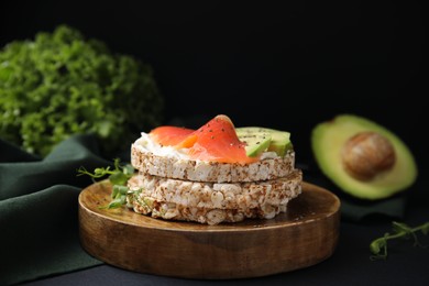 Photo of Crunchy buckwheat cakes with cream cheese, salmon and avocado on black table