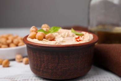 Photo of Delicious hummus with chickpeas and paprika served on white wooden table, closeup