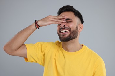 Photo of Handsome young man laughing on grey background