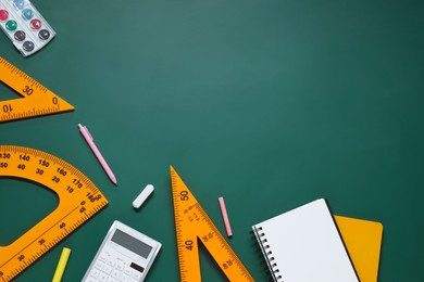 Photo of Flat lay composition with protractor, triangle and stationery on green chalkboard. Space for text