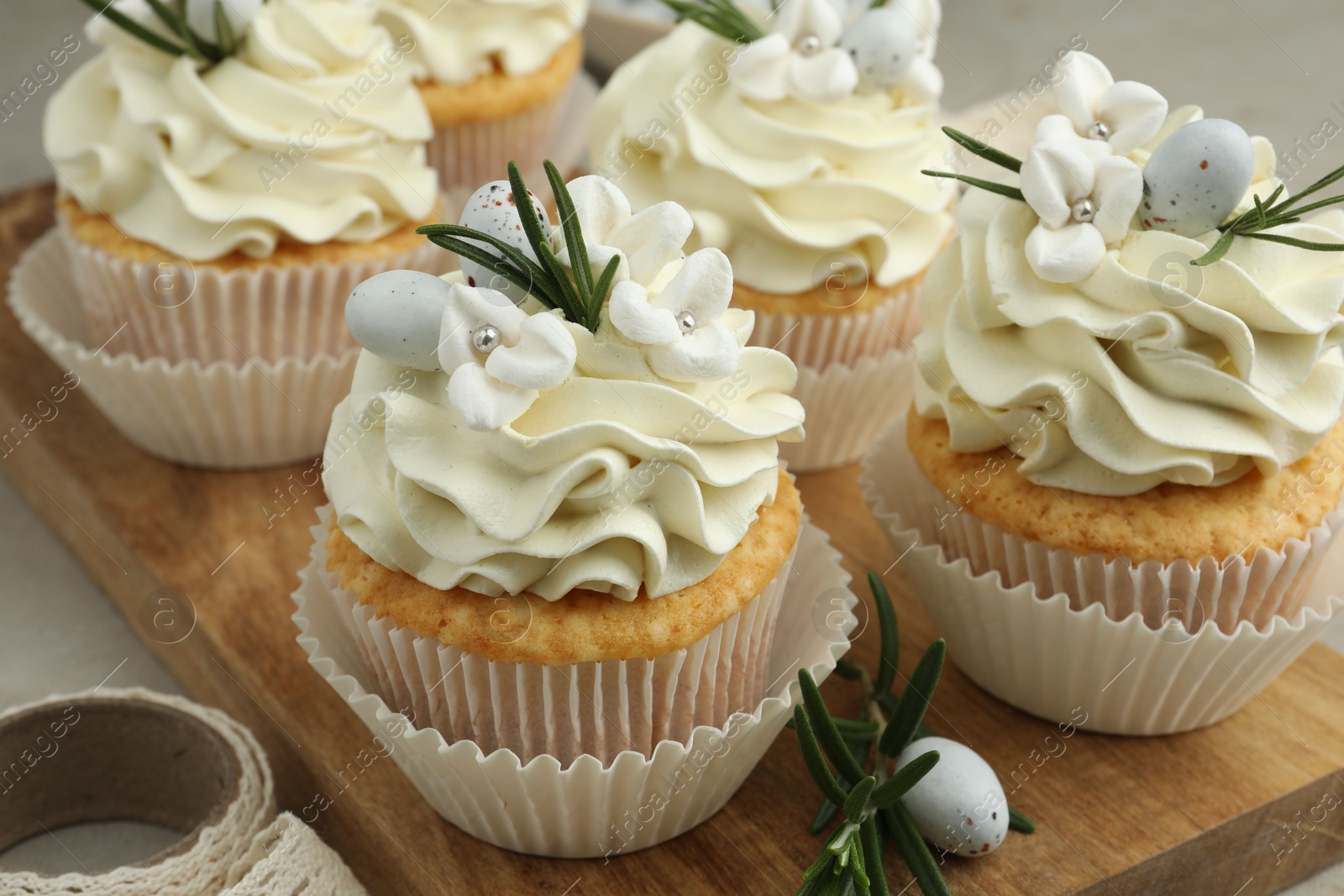 Photo of Tasty Easter cupcakes with vanilla cream on table, closeup