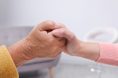 Photo of People holding hands together indoors. Help and elderly care service