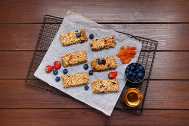 Photo of Tasty granola bars and ingredients on wooden table, flat lay