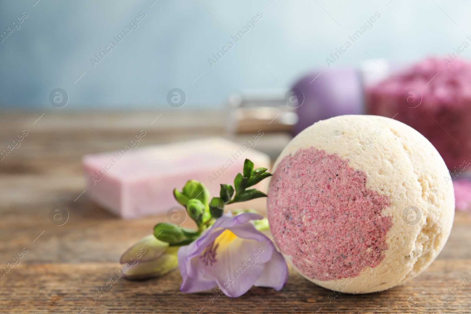 Photo of Bath bomb and flower on wooden table. Space for text
