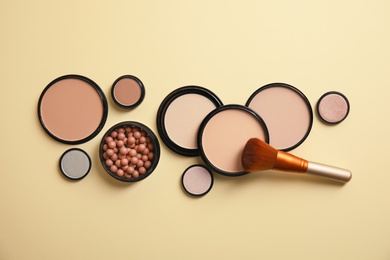 Flat lay composition with various makeup face powders on color background