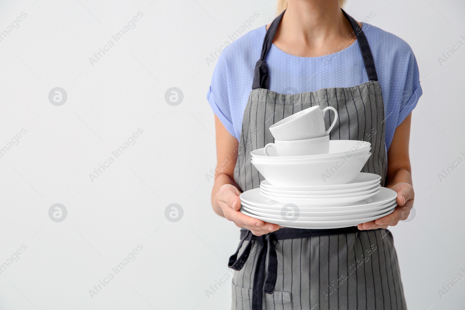 Photo of Woman with clean dishes and cups on white background, closeup. Space for text