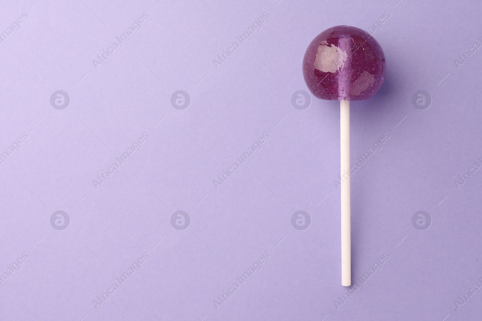 Photo of Tasty lollipop on violet background, top view. Space for text