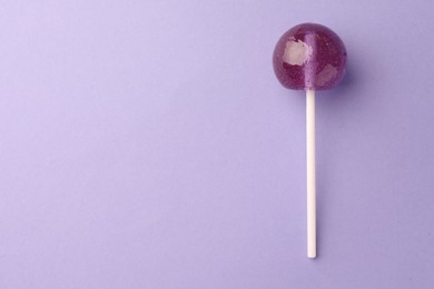 Photo of Tasty lollipop on violet background, top view. Space for text