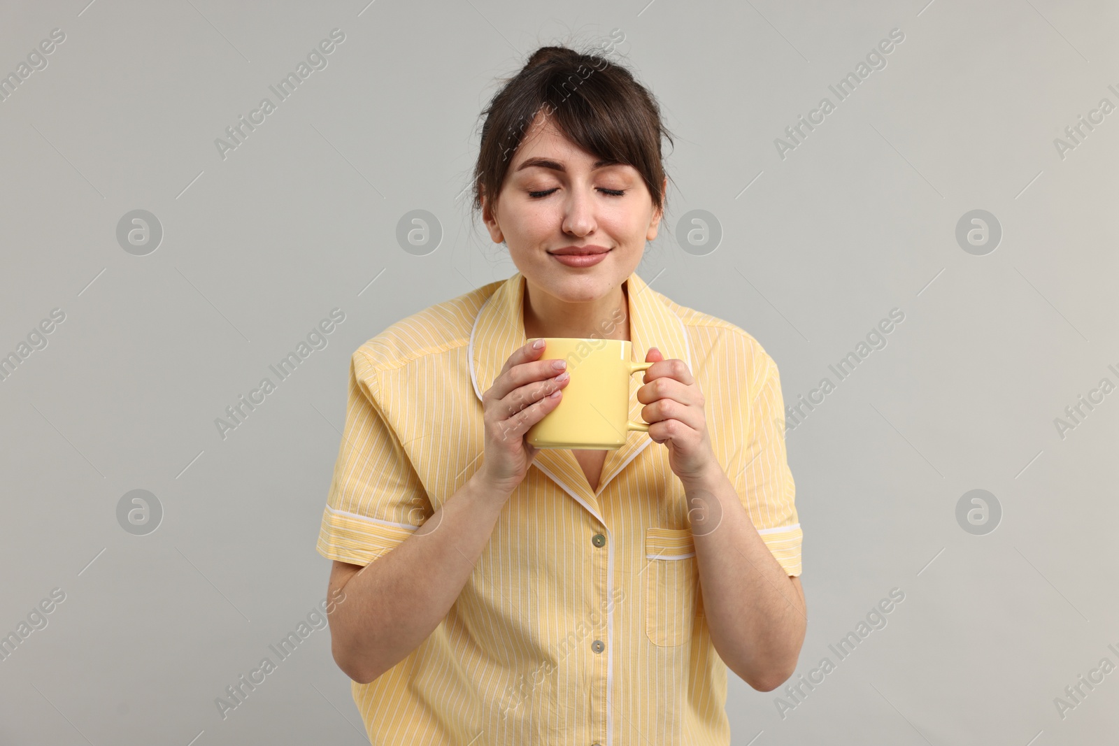 Photo of Woman in pyjama holding cup of drink on grey background