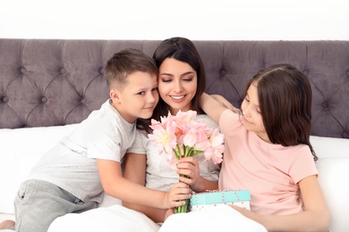 Photo of Son and daughter congratulating mom in bed. Happy Mother's Day