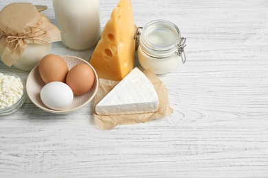 Different dairy products on white wooden table. Space for text