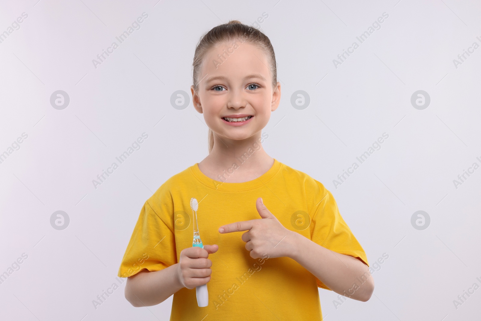 Photo of Happy girl holding electric toothbrush on white background