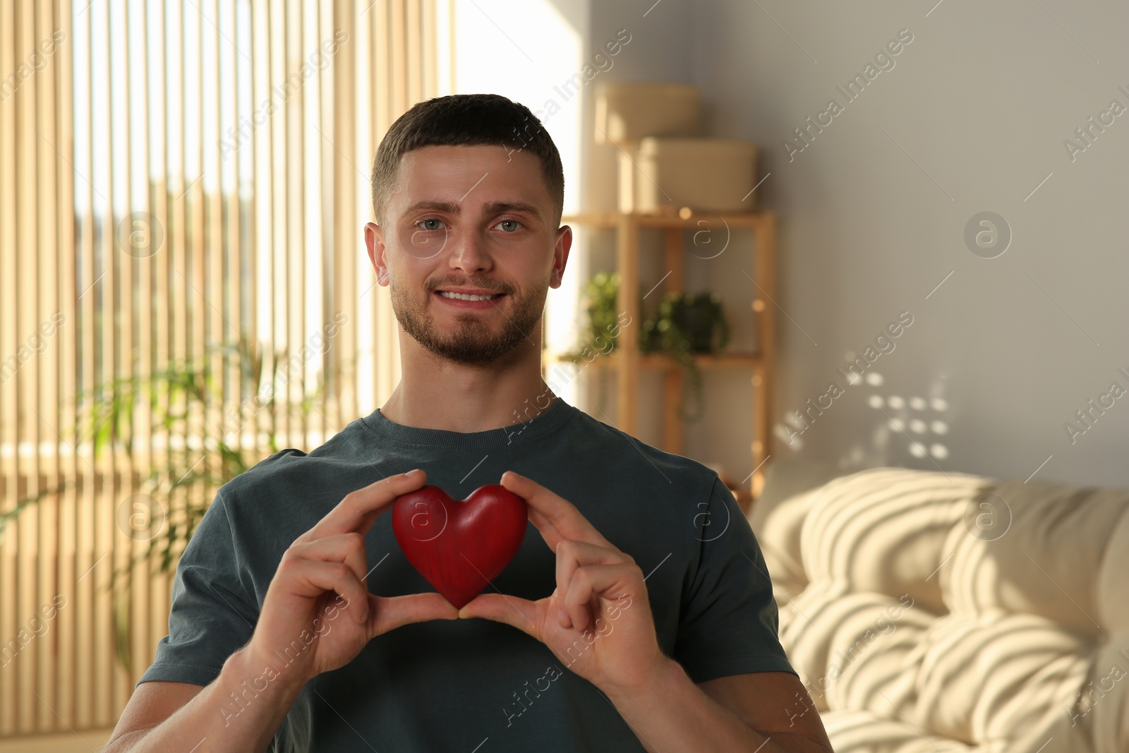 Photo of Happy volunteer holding red heart with hands indoors