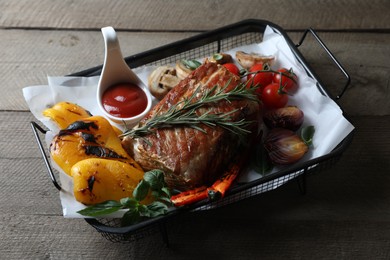 Photo of Delicious grilled meat and vegetables served with sauce on wooden table