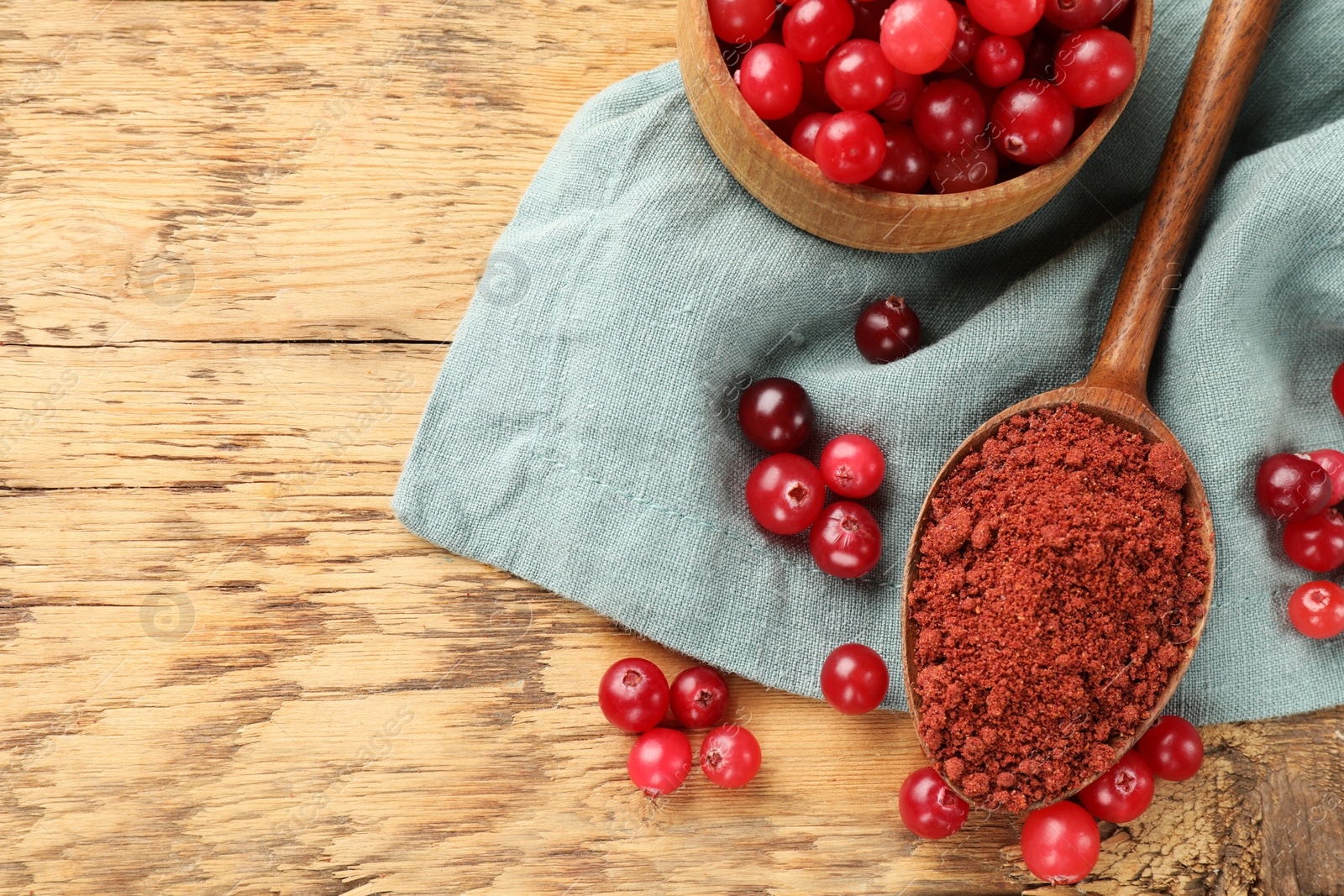 Photo of Spoon with cranberry powder and fresh berries on wooden table, top view. Space for text