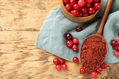 Photo of Spoon with cranberry powder and fresh berries on wooden table, top view. Space for text