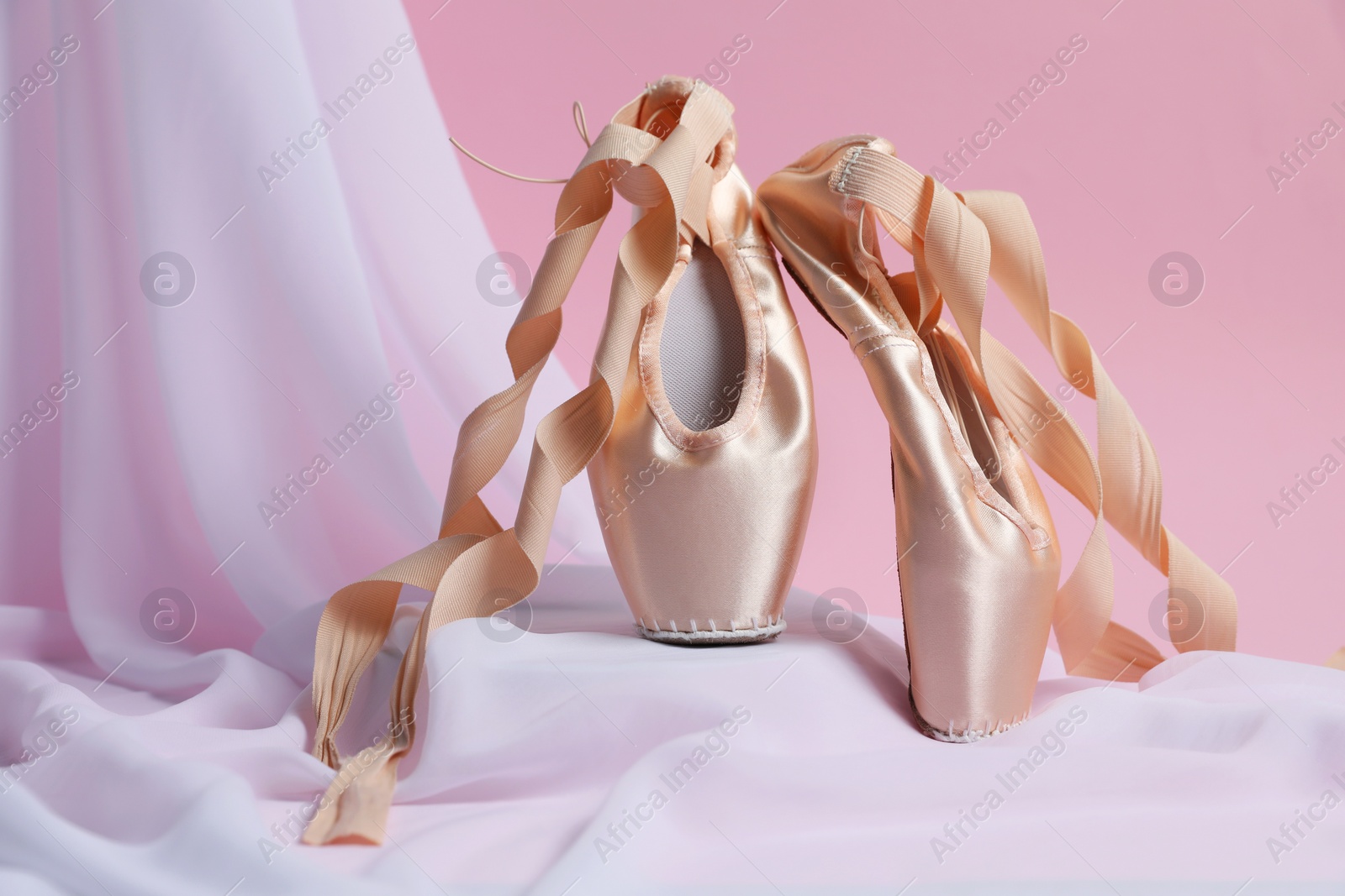 Photo of Ballet shoes. Stylish presentation of elegant pointes on pink background