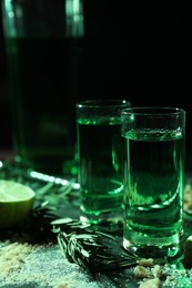 Absinthe in shot glasses, rosemary and brown sugar on table, closeup. Alcoholic drink