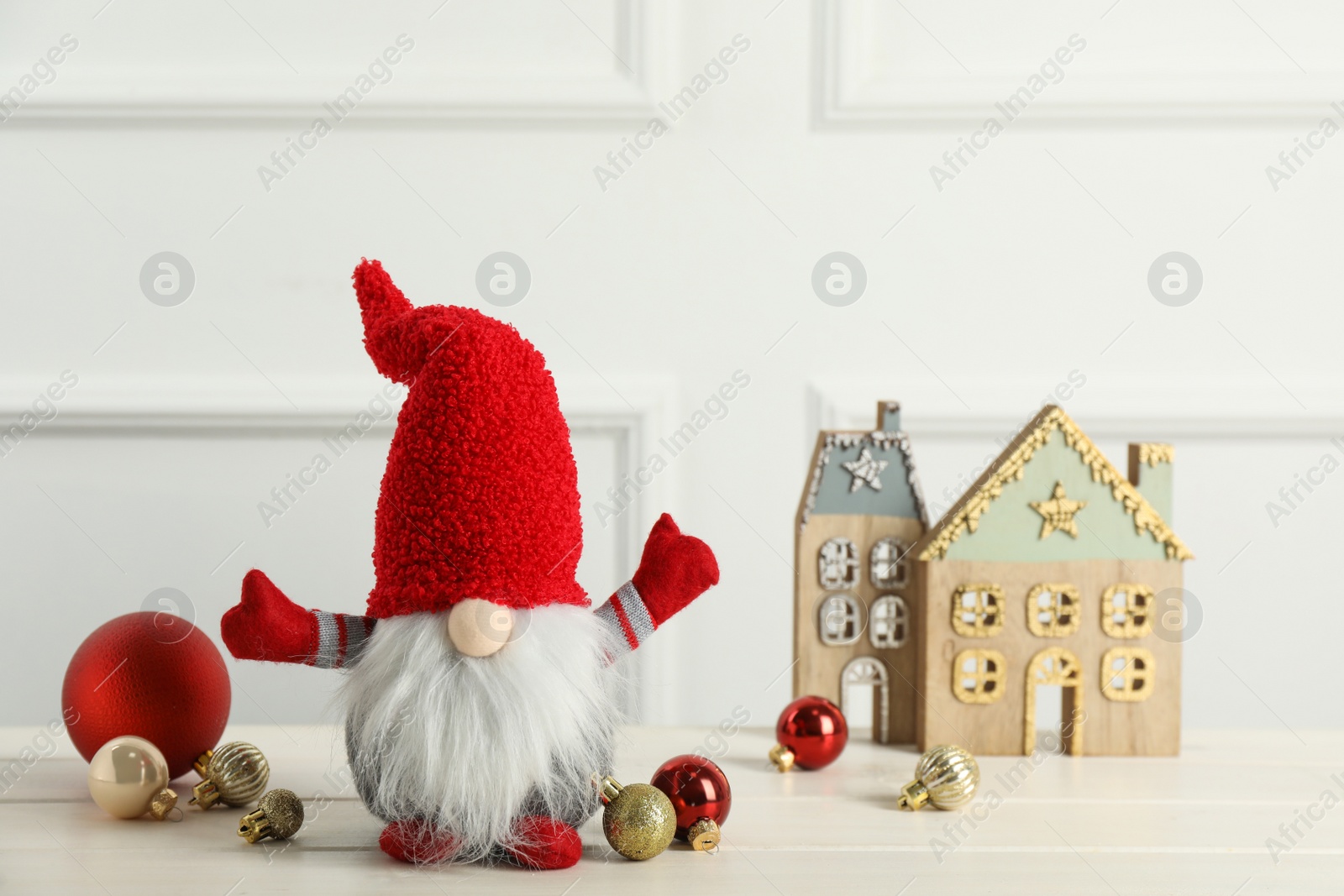 Photo of Cute Christmas gnome and festive decor on white wooden table