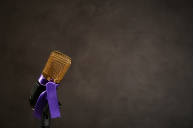 Microphone with purple awareness ribbon on dark background, space for text