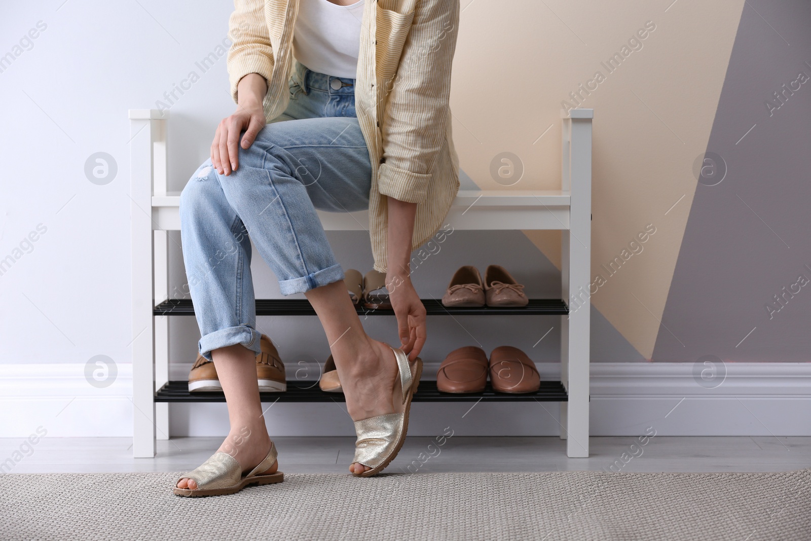 Photo of Woman putting on shoes indoors, closeup. Stylish hallway interior