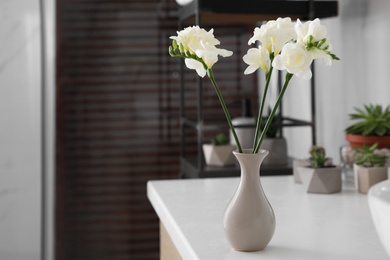 Beautiful white freesia flowers in vase on table indoors