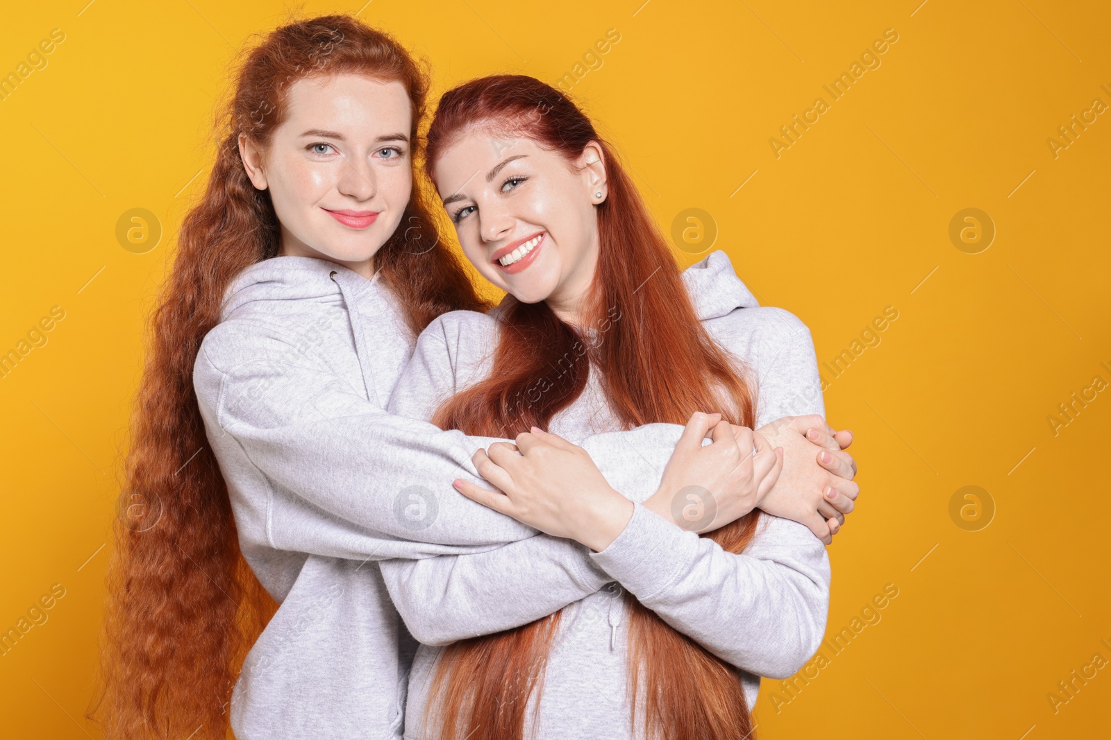 Photo of Portrait of beautiful young redhead sisters on orange background
